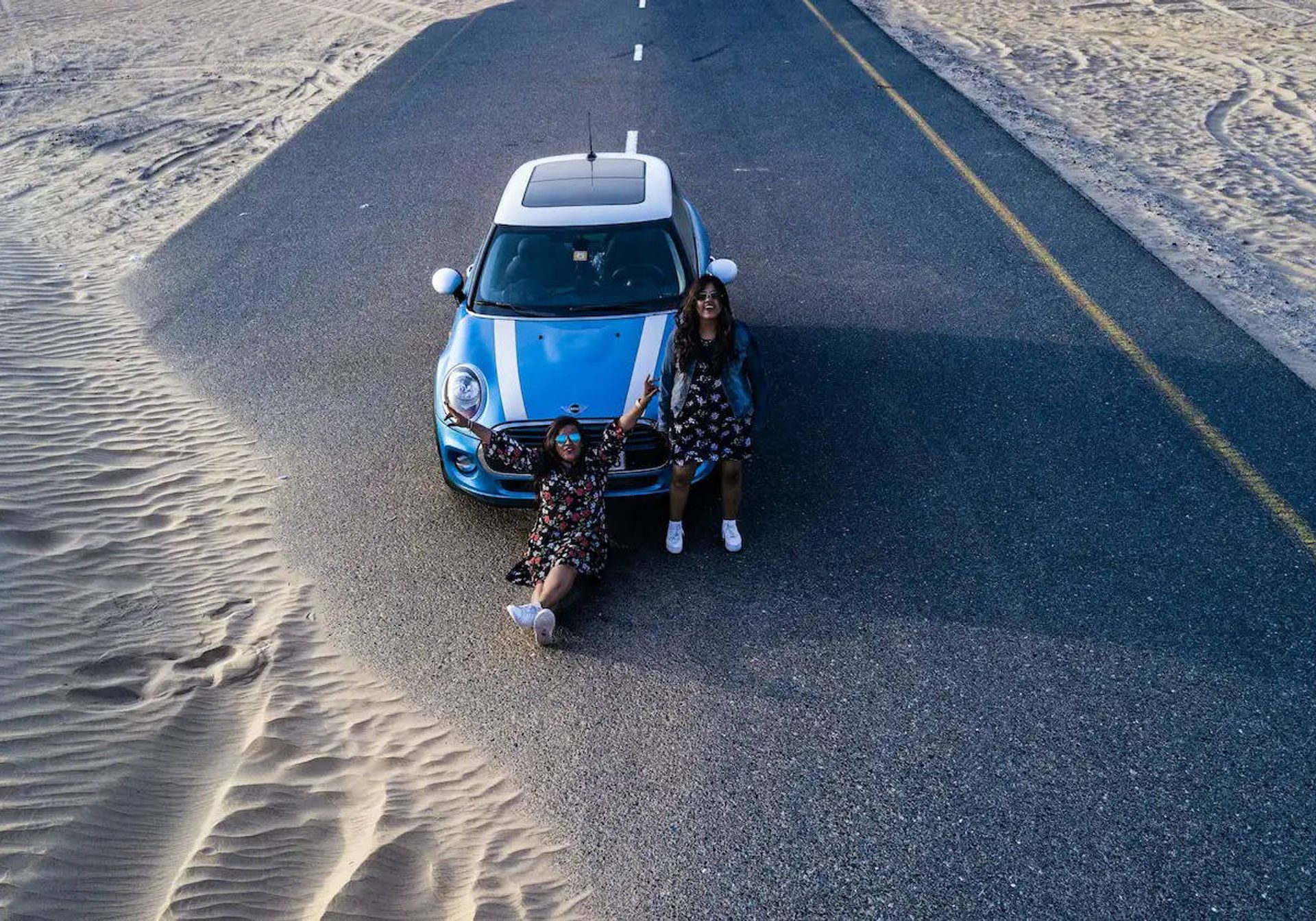 Women with Mini on desert road from drone perspective