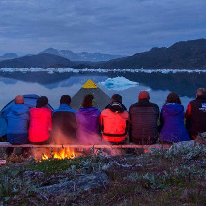friends with fire overlooking lake in greenland