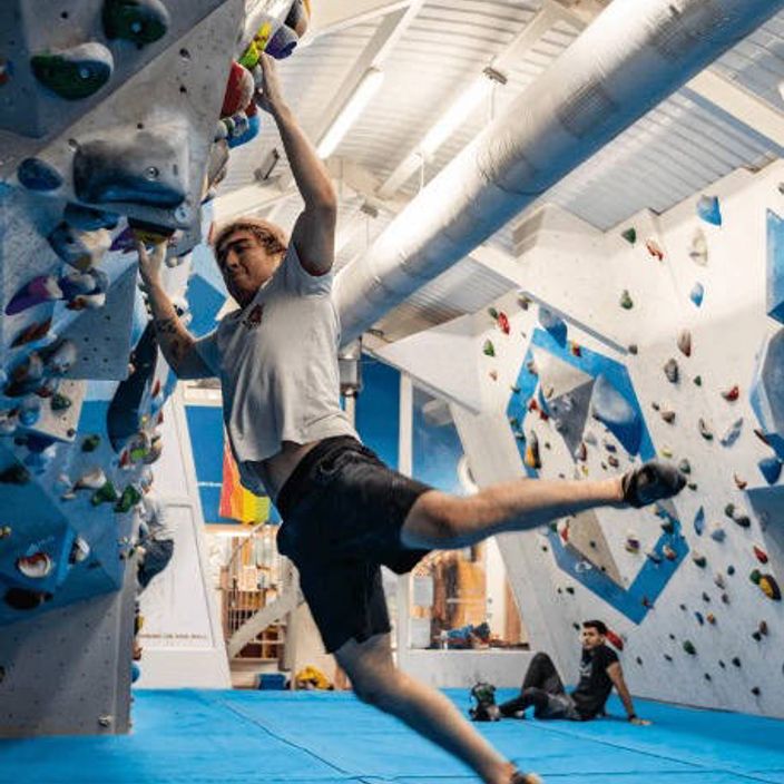 A climber attempts a tricky manoeuvre on a climbing wall