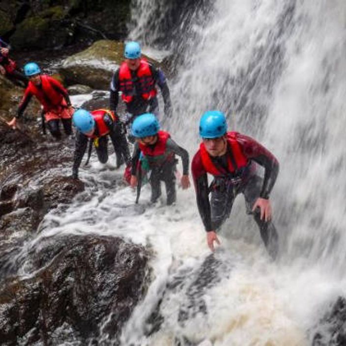 family walking through waterfall in wales