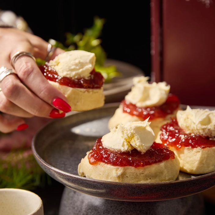 hand grabbing a scone with jelly and vegan cream