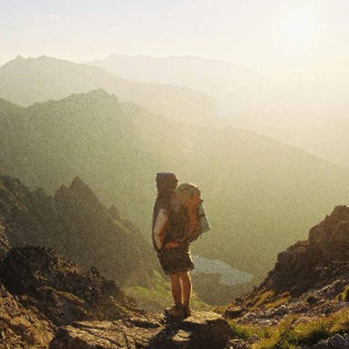 Person with a backpack stares out at a mountain landscape