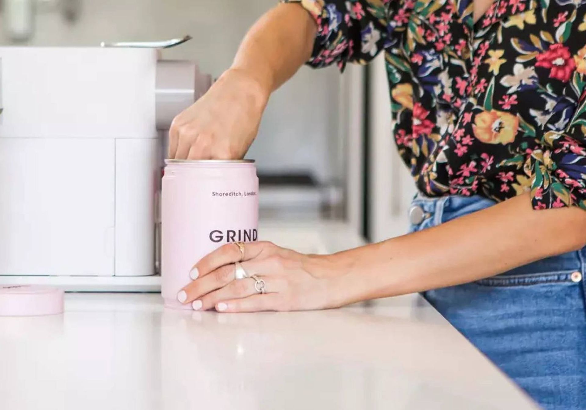Woman scooping coffee out of GRIND coffee tin