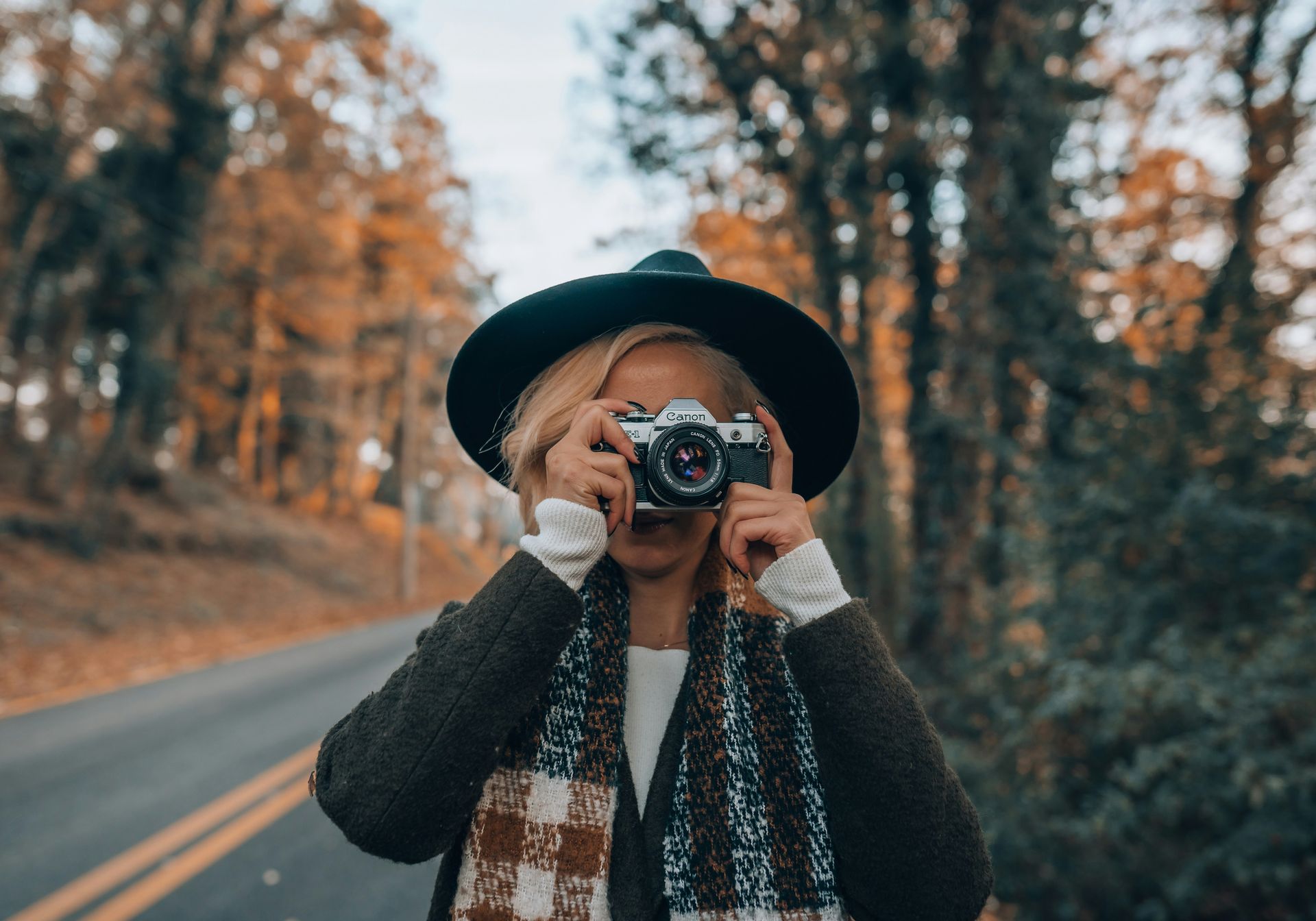 Lady holds the Canon AE-1 camera smiling