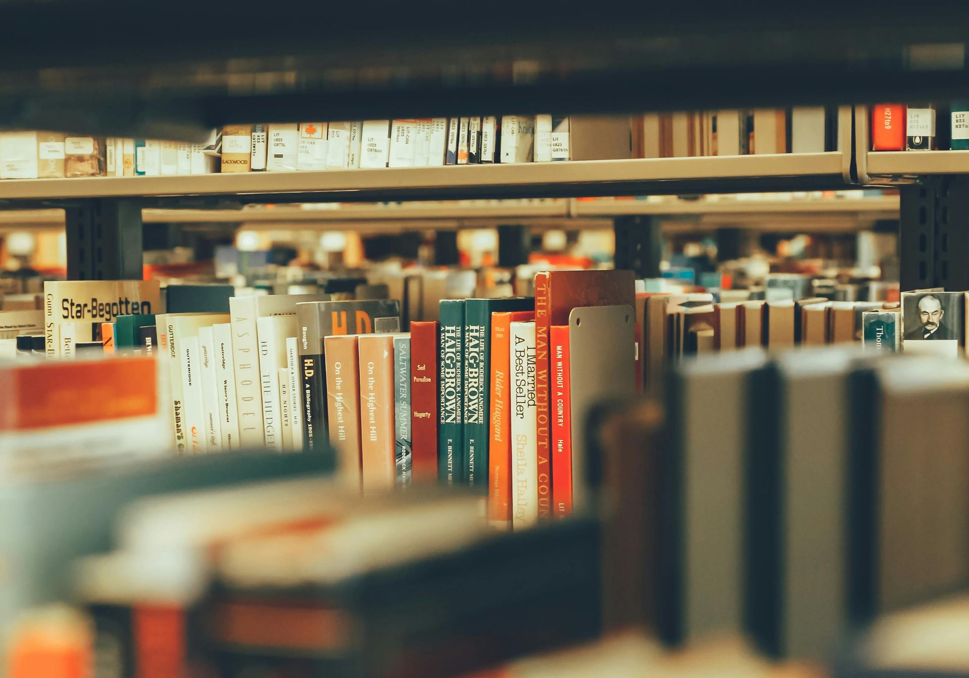 Person using Macbook with book on table