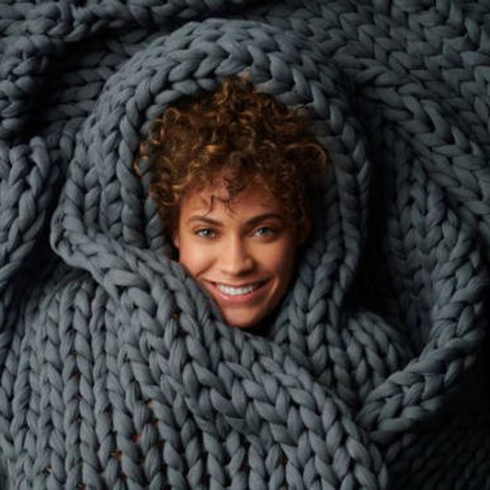 Woman's face peeking out of a Bearaby cotton weighted blanket