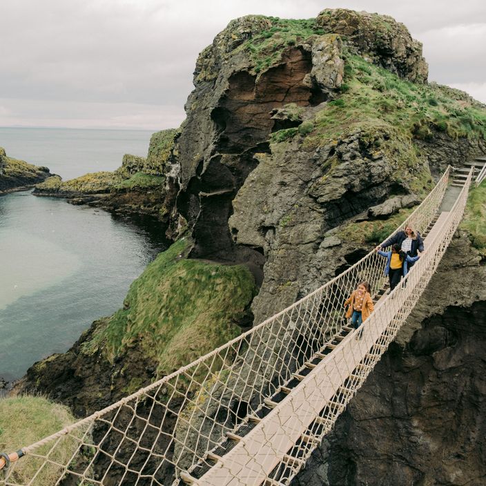 Three people walk over a footbridge in the Giant's Causeway