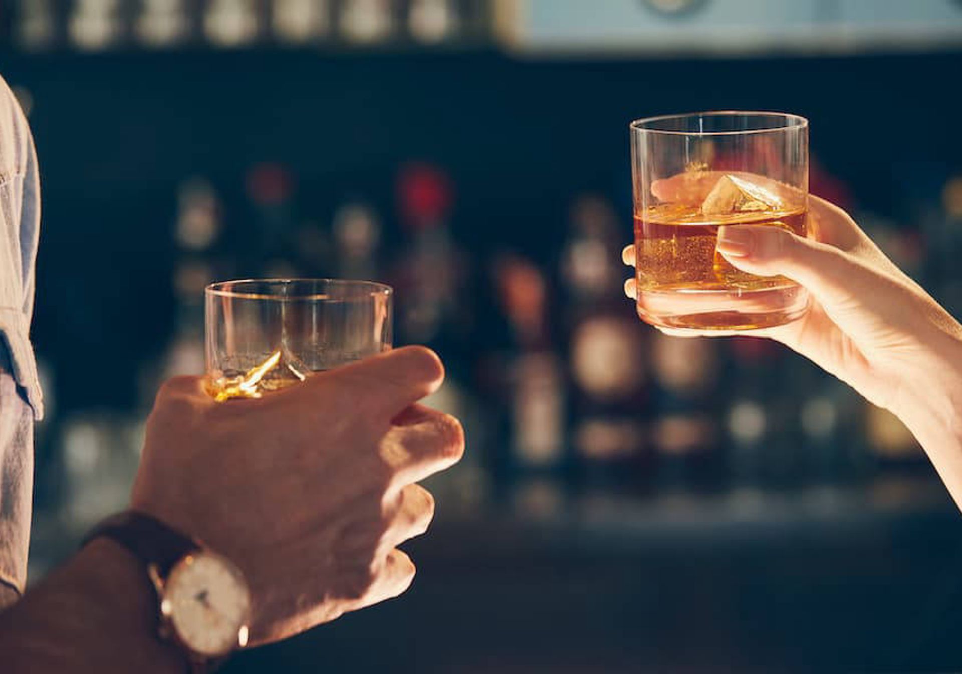 Two people holding glasses of whisky