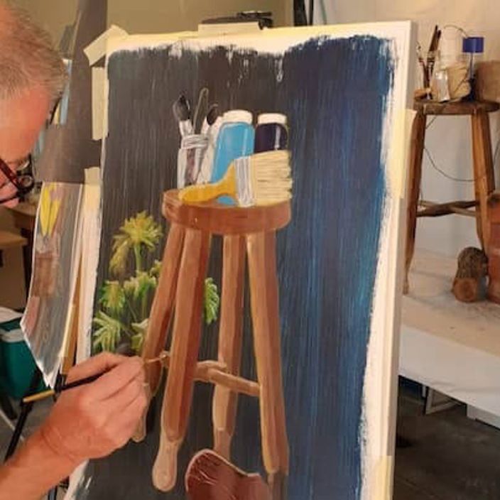 A man painting a wooden stool