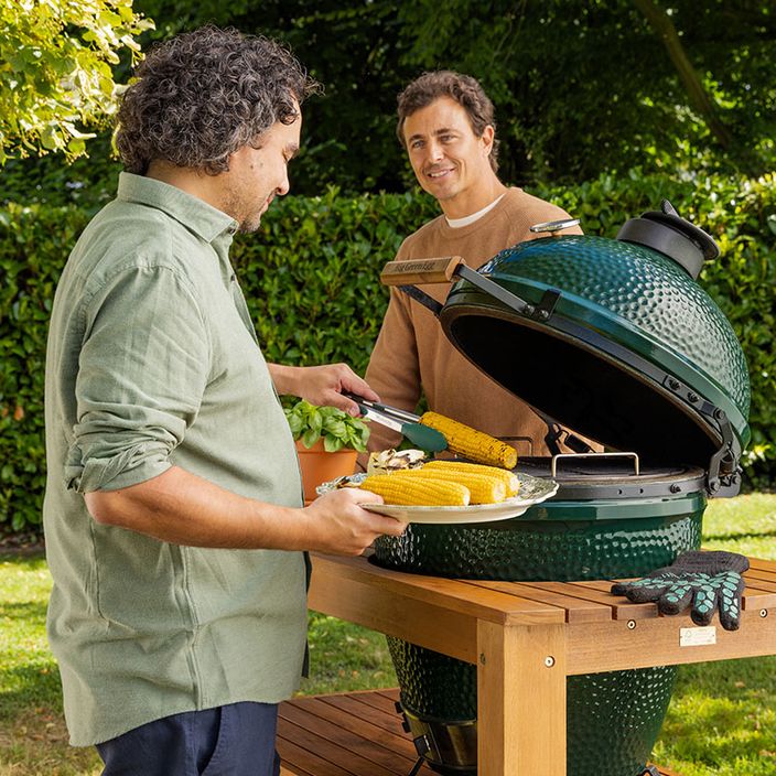 man looking at woman and grilling corn on a big green egg bbq