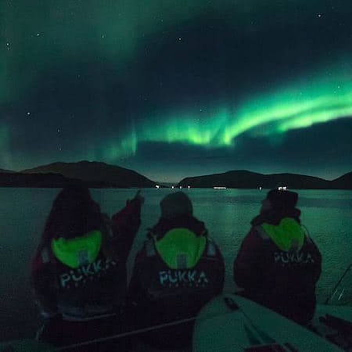 Three people watching the Northern Lights