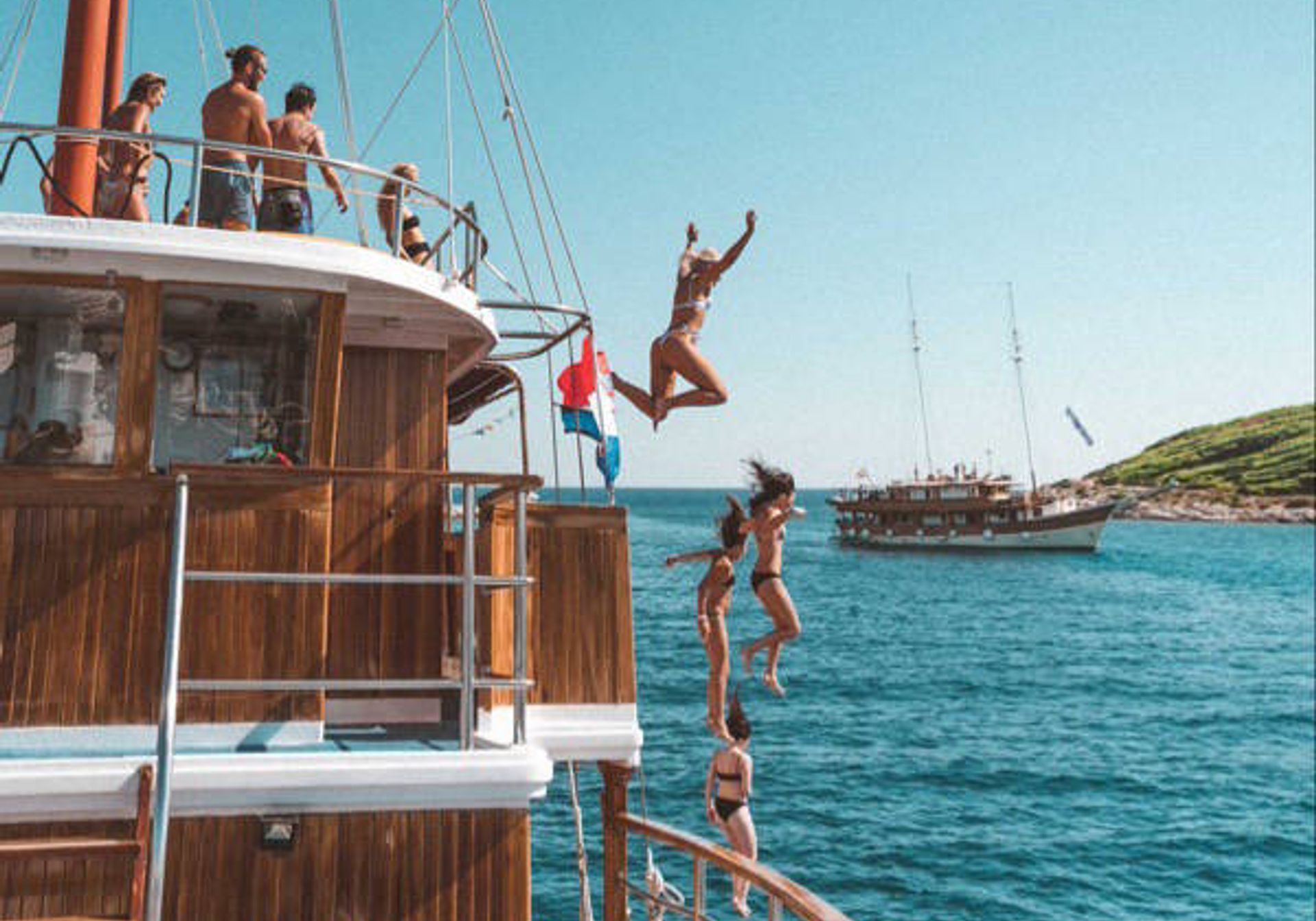 People jumping off a yacht into blue waters