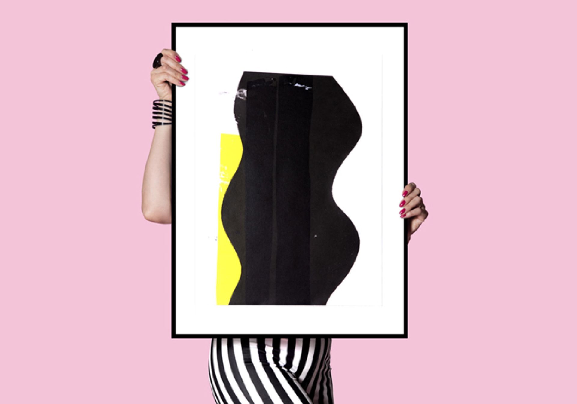 Woman holding a painting in front of a pink background