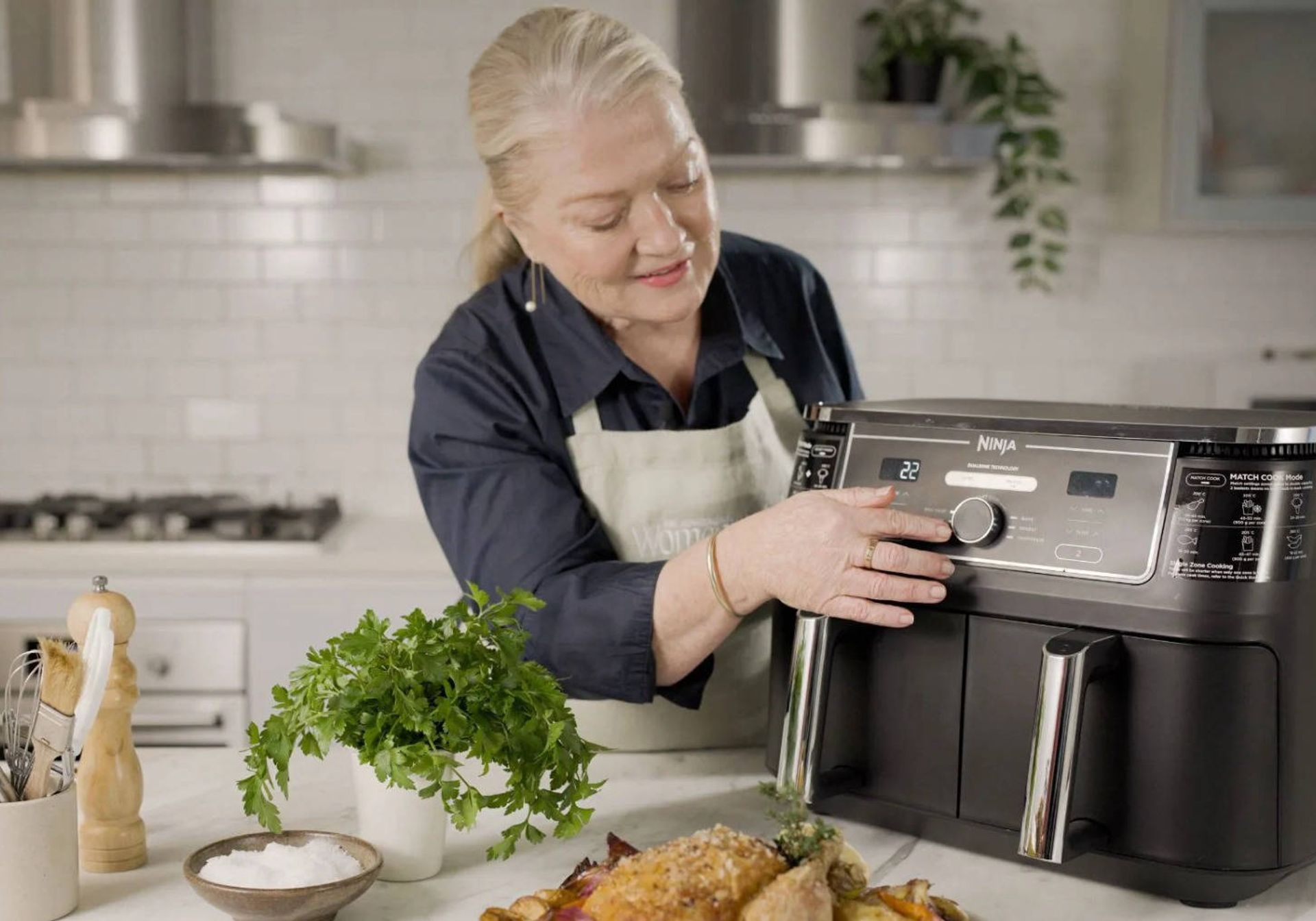Women taking salmon out of a air fryer and putting it on a plate. 