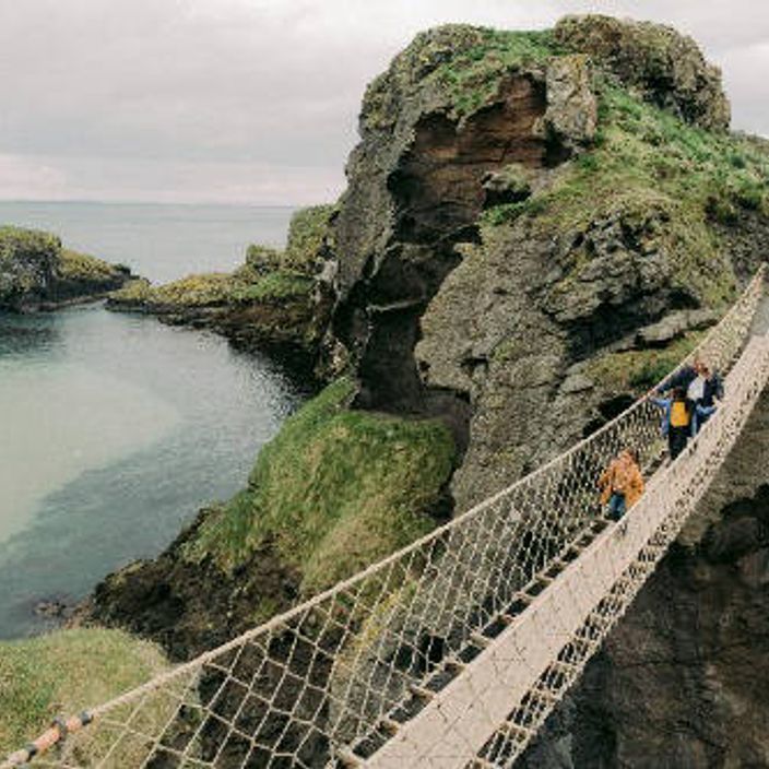 Three people walk over a footbridge in the Giant's Causeway