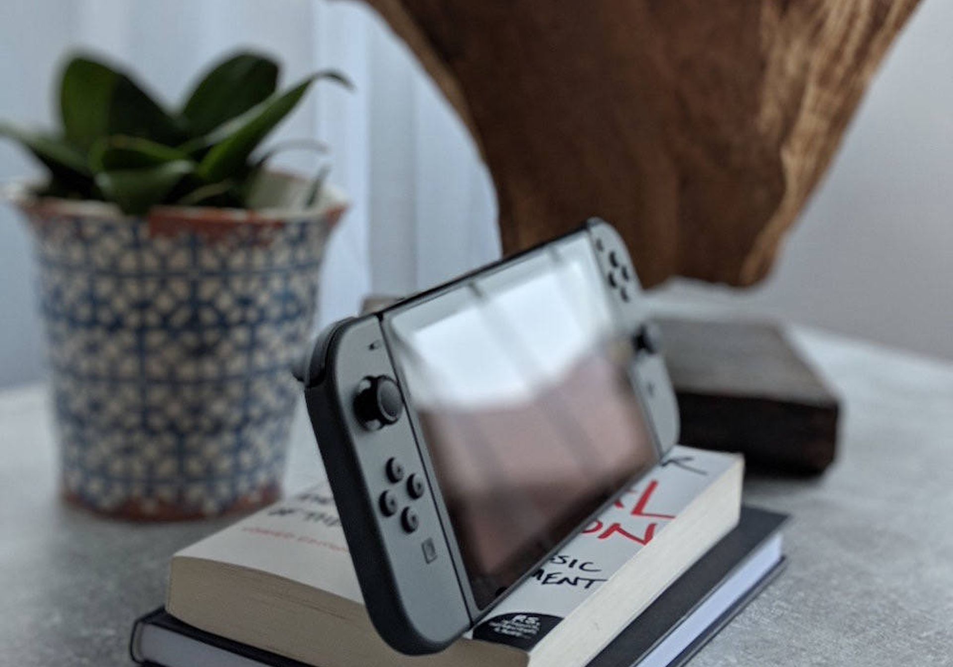 Nintendo switch console on a table with books and plants