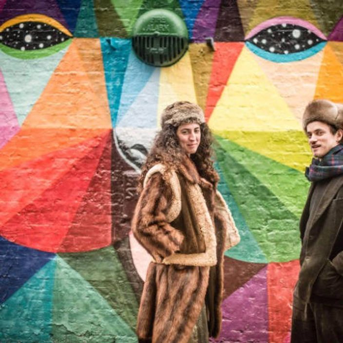 Woman and man standing in front of colourful wall