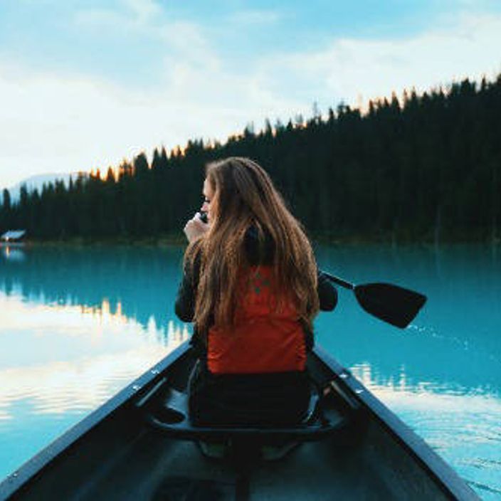 A girl canoes on a lake in Canada