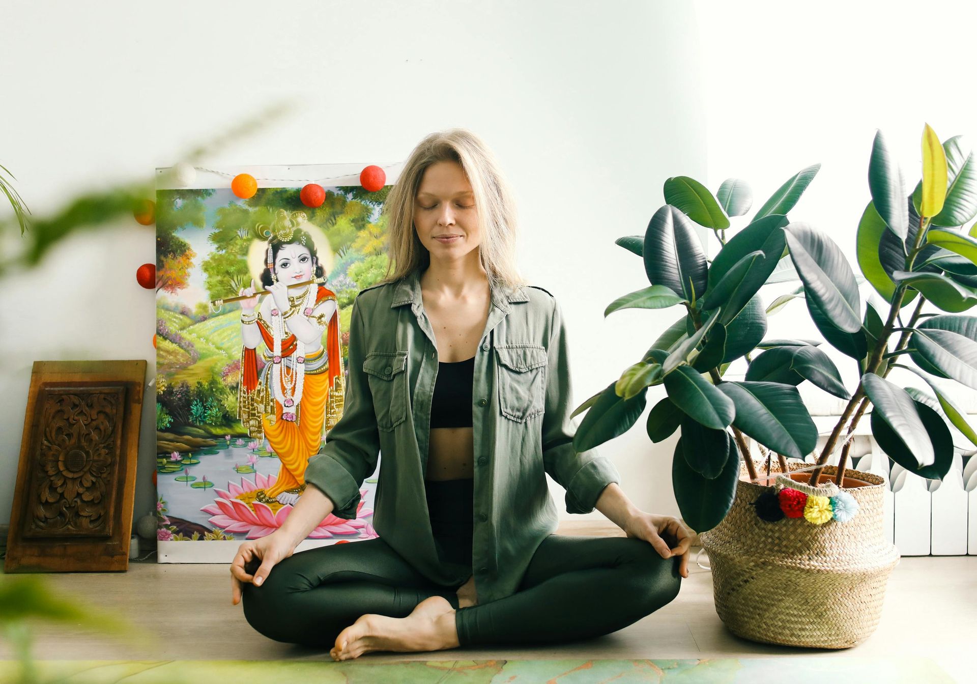 a black woman with her hair in a bun in a zen pose enjoying meditation