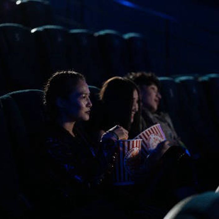 Friends watching a movie at the cinema and eating popcorn